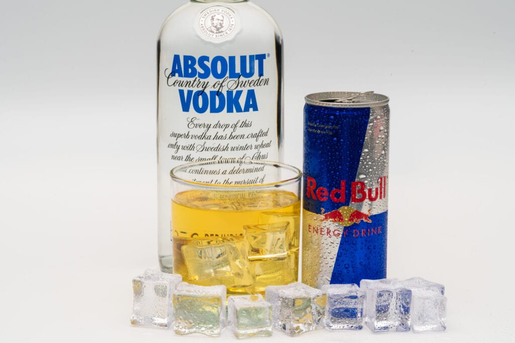 Aluminium can of Red Bull Energy drink with ice and drops, Vodka Absolut.